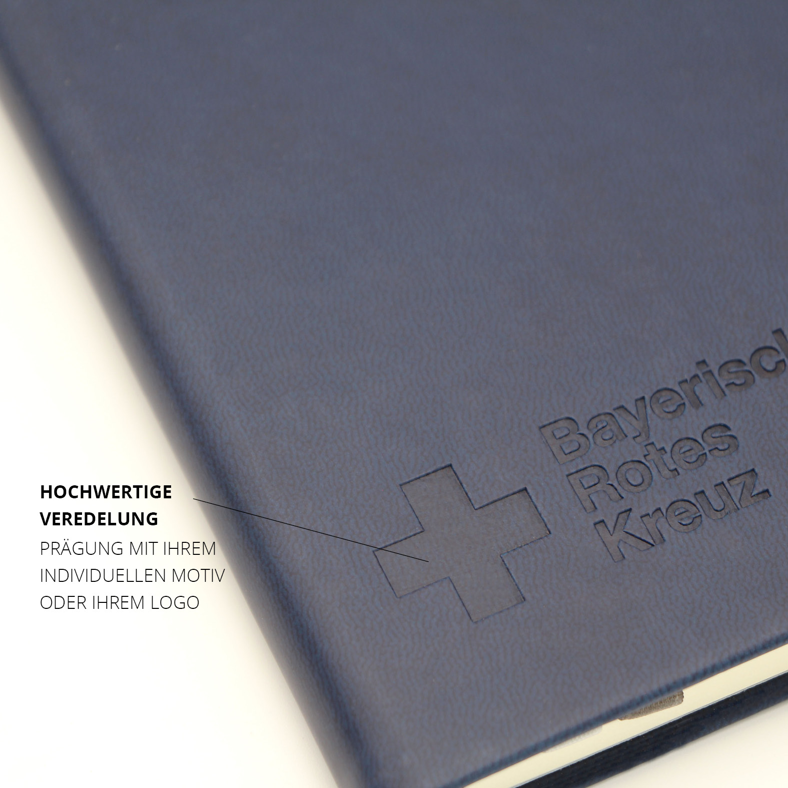 Vorderansicht des dunkelblauen Einbands mit Blindprägung „Bayerisches Rotes Kreuz“ und Kreuzsymbol, strukturierte Oberfläche des Kunstleders sichtbar.