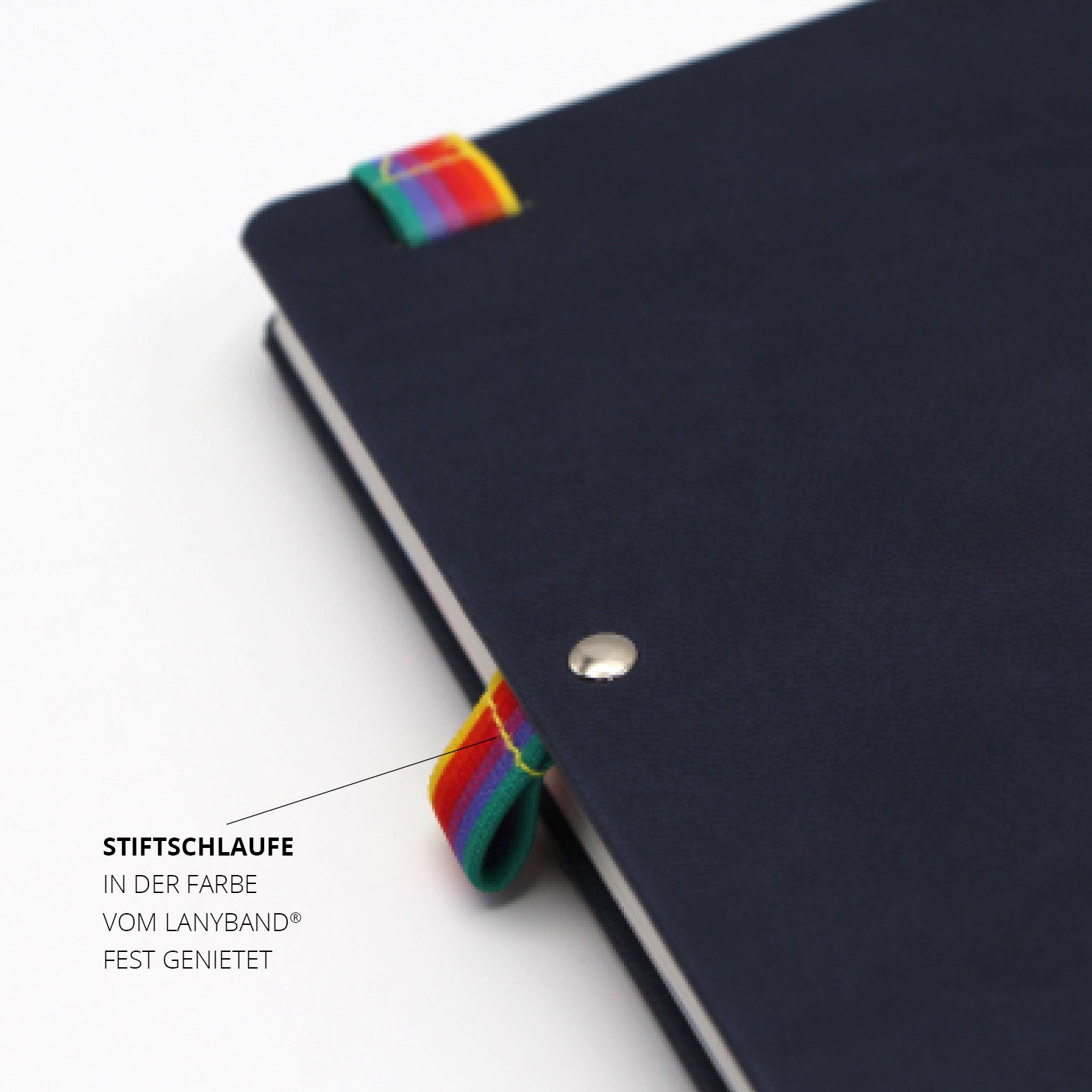  Detail der genieteten Stiftschlaufe aus regenbogenfarbenem Band auf der Rückseite des Lanybooks. Daneben die metallene Niete als Verstärkung.