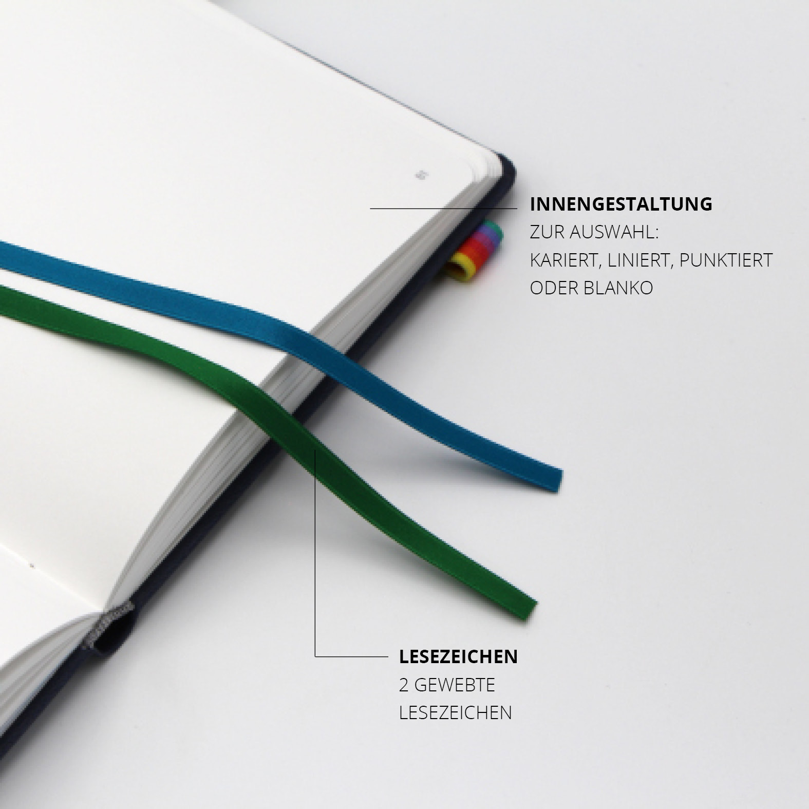 Zwei gewebte Lesezeichen in Blau und Grün liegen auf den Innenseiten des Notizbuchs. Rechts sichtbar: das bunte Lanyband® mit elastischer Stiftschlaufe. Auswahlmöglichkeiten: kariert, liniert, punktiert oder blanko.