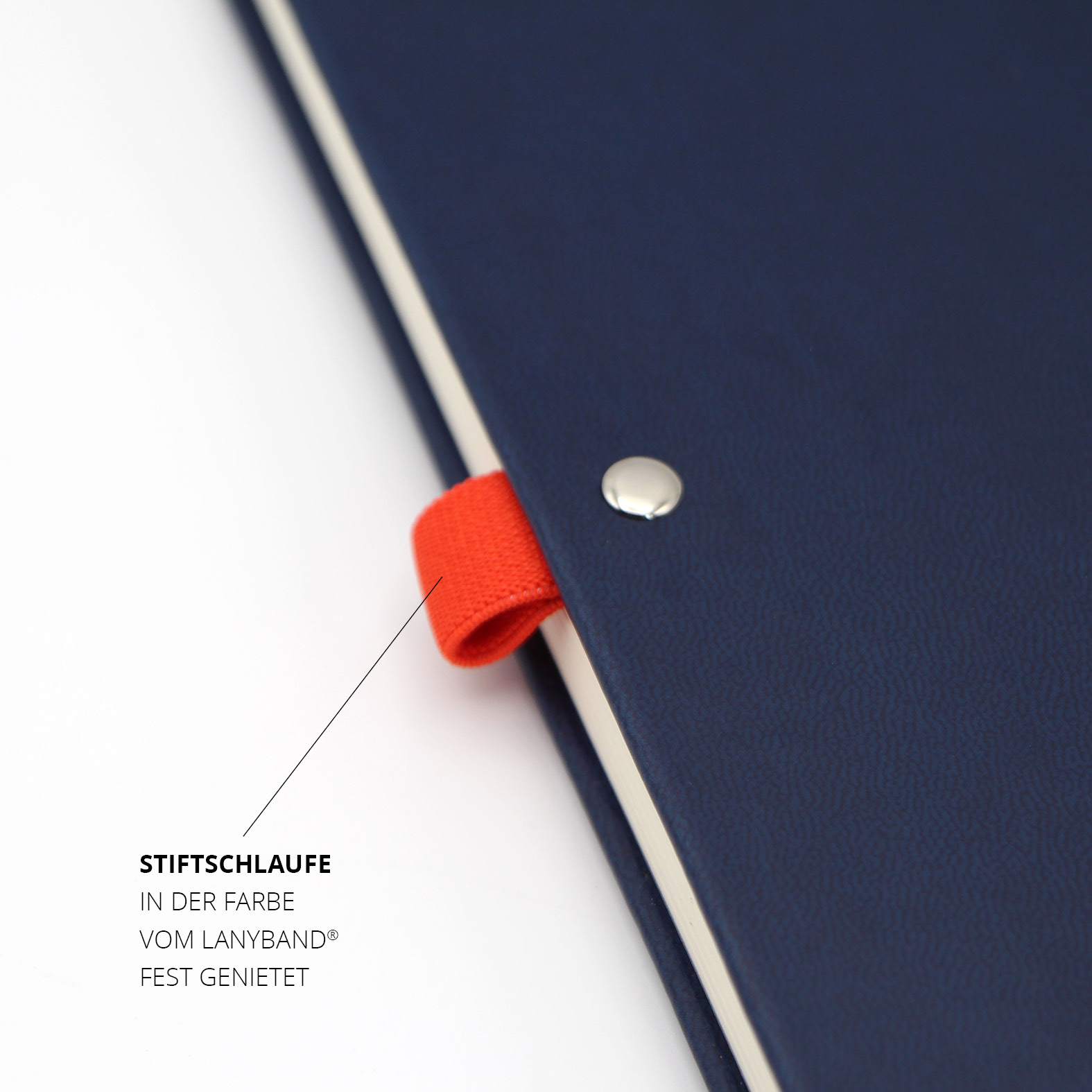 Nahaufnahme der fest vernieteten Stiftschlaufe in Lanyband®-Farbe auf dem dunkelblauen Einband, silberner Nietenkopf sichtbar.