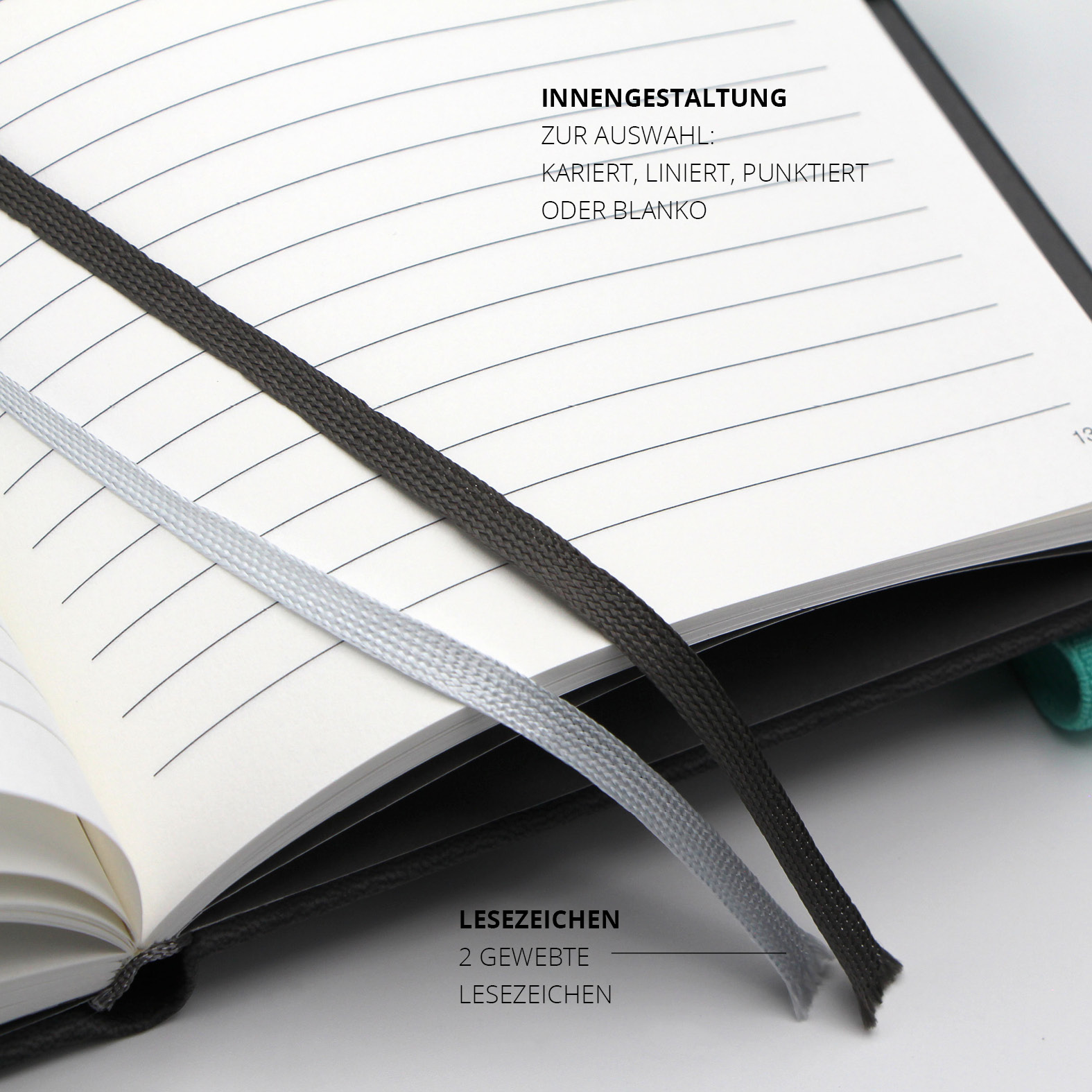 Zwei gewebte Lesezeichenbänder in Schwarz und Silber auf linierter Innenseite des Notizbuchs.