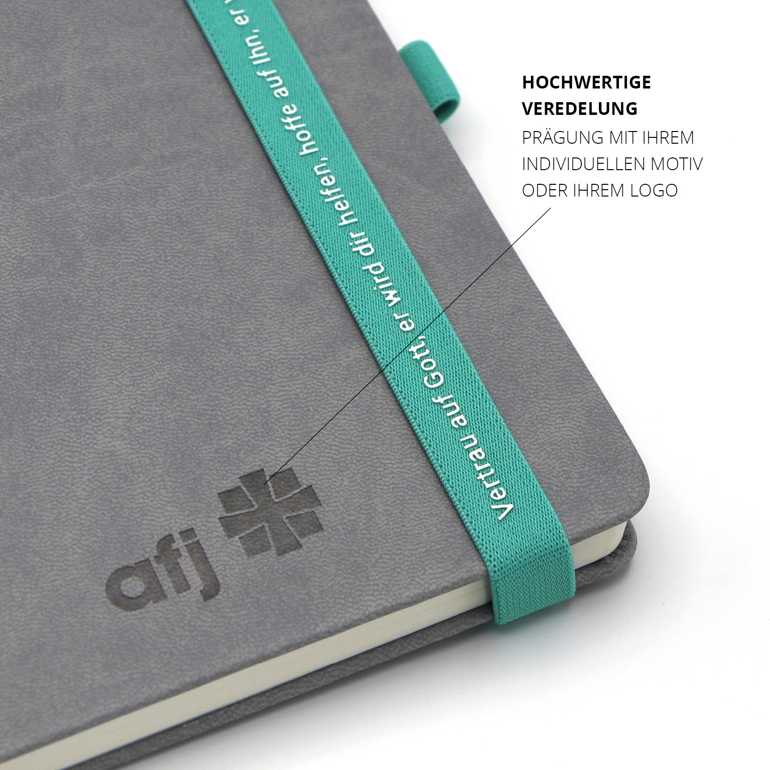 Detail der schwarzen Blindprägung des afj-Logos auf dem grauen Kunstledereinband neben dem personalisierten Lanyband.