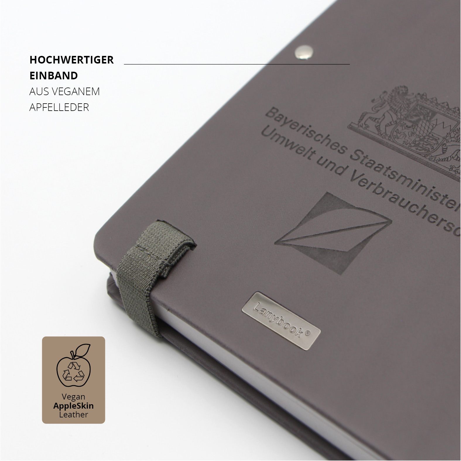 Nahaufnahme des hochwertigen Einbands aus veganem Apfelleder mit Logo-Prägung des Bayerischen Staatsministeriums.