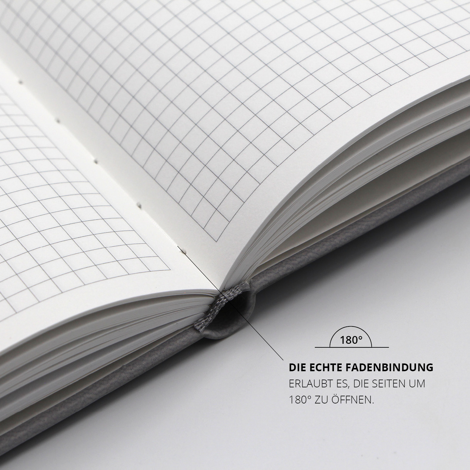 Blick auf die Innenseiten des Notizbuchs mit kariertem Recyclingpapier und echter Fadenbindung für ein flaches Aufschlagen bis 180 Grad.