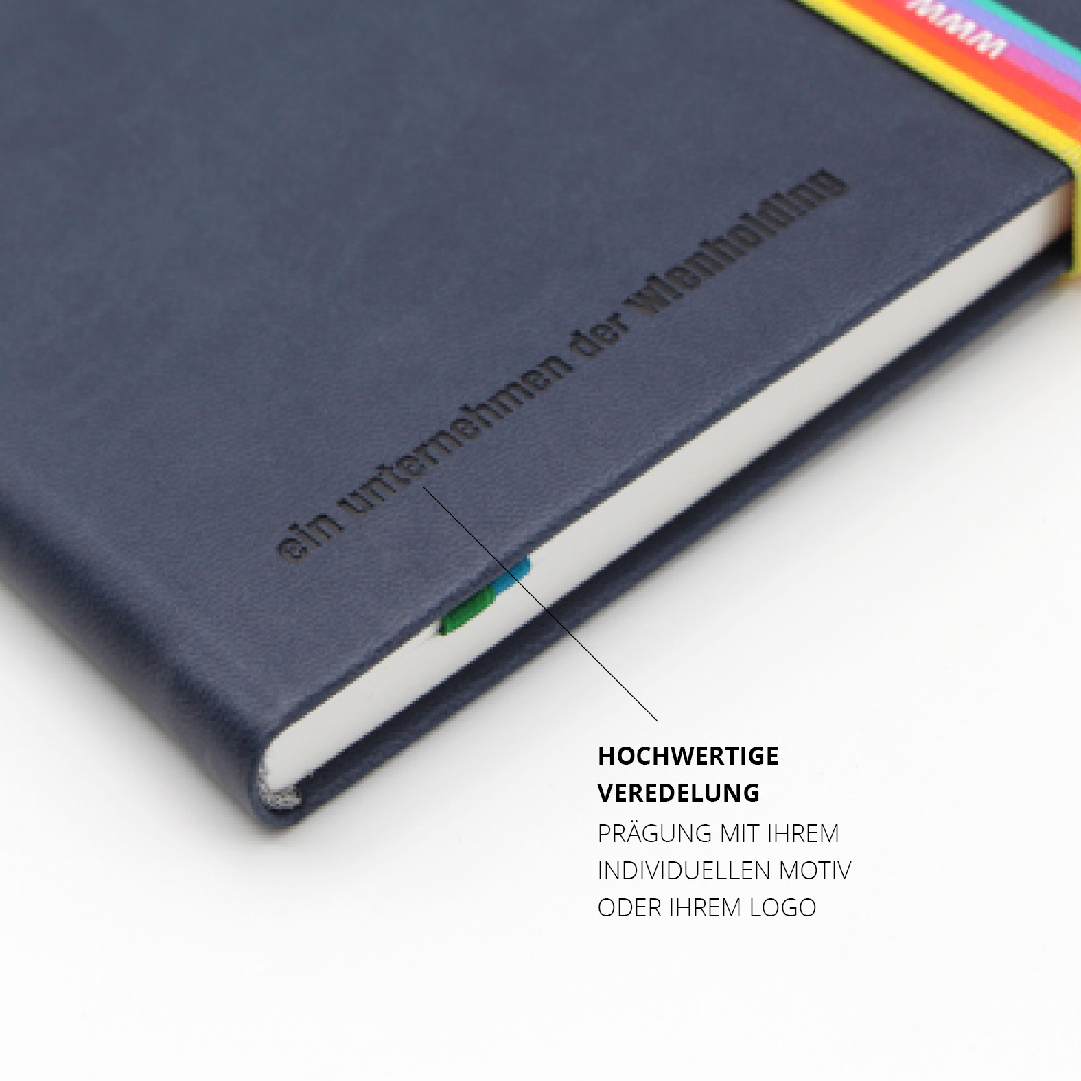 Detailaufnahme des unteren Covers mit der Prägung „ein unternehmen der wienholding“. Die Prägung ist tiefschwarz auf dunkelblauem Kunstleder. Teil des grünen Lesezeichens sichtbar.