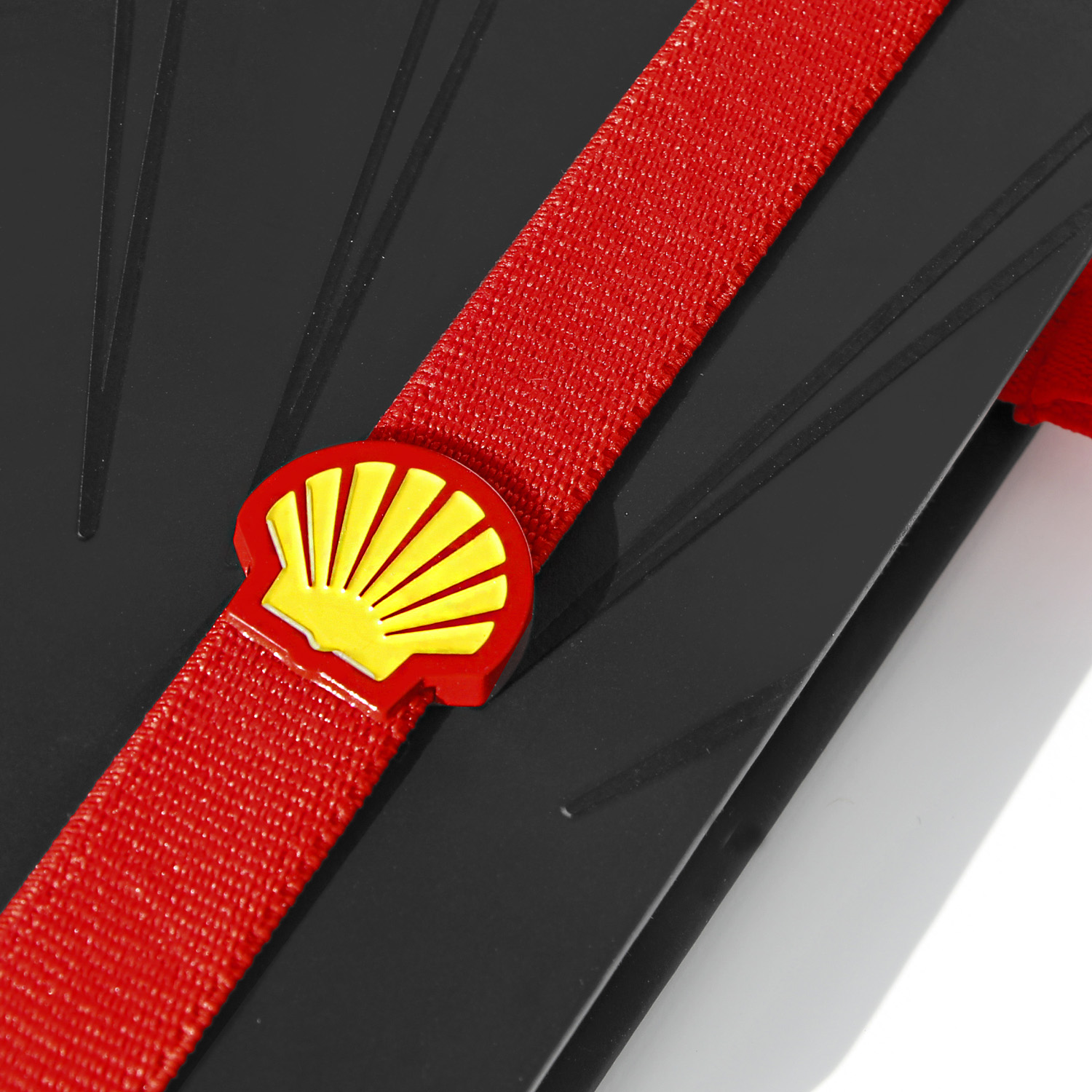 Nahaufnahme eines schwarzen Notizbuchs mit rotem Lanyband, das eine gelb-rote Shell-Logo-Applikation enthält.