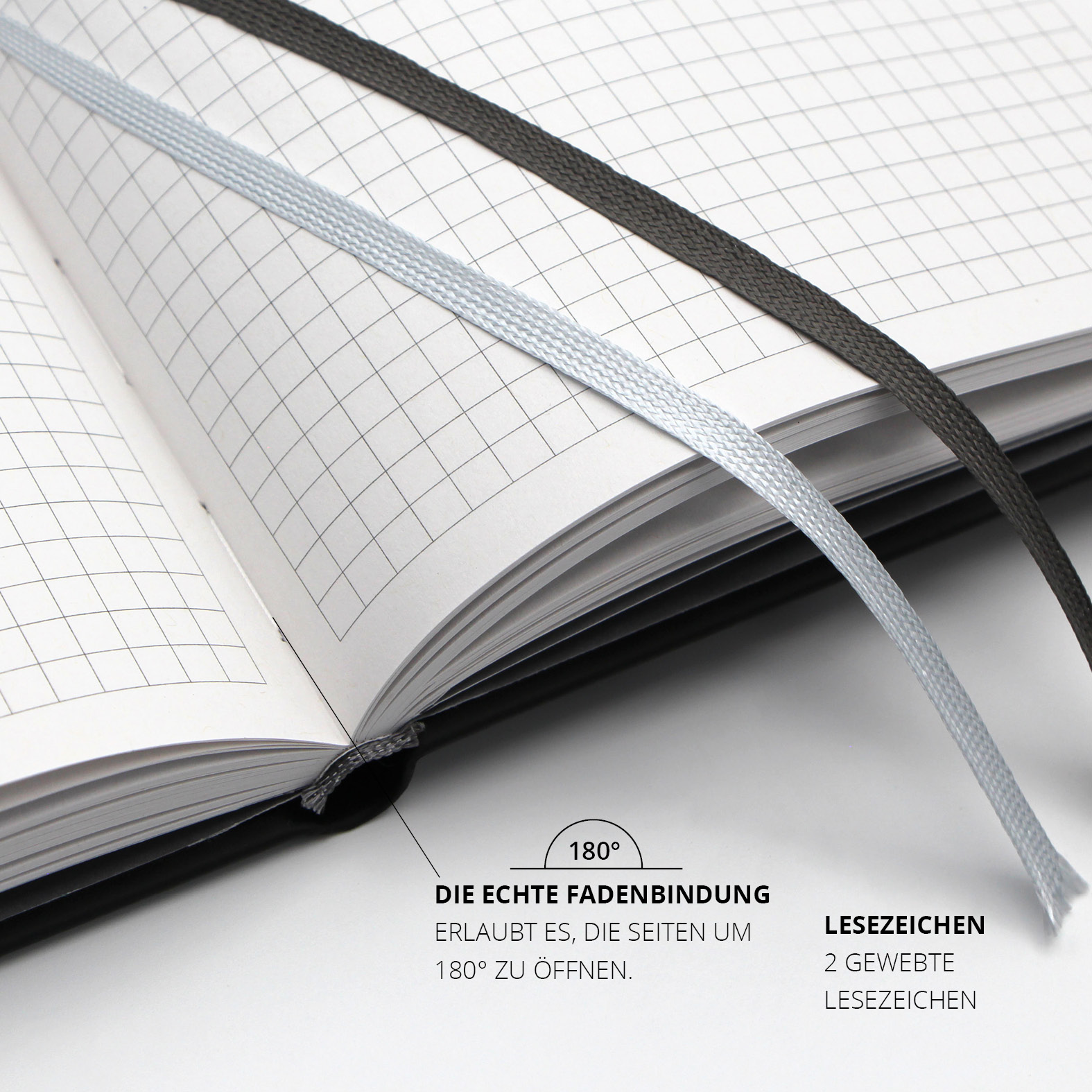 Geöffnete Doppelseite des Lanybooks® mit kariertem Innenlayout, zwei gewebten Lesezeichenbändern in Hellgrau und Dunkelgrau und echter Fadenbindung.