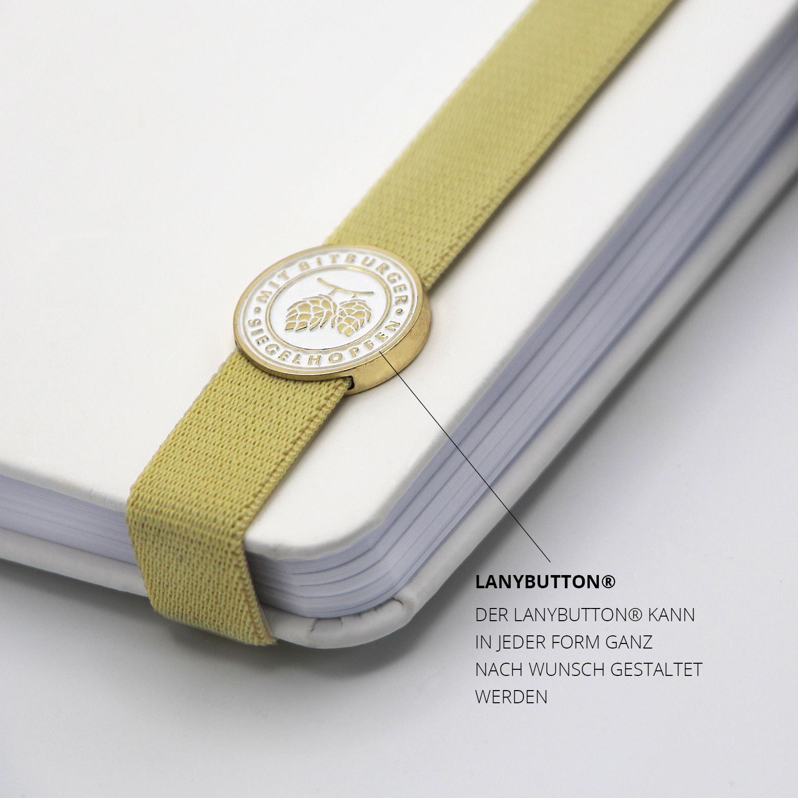 Geprägter Lanybutton® mit Bitburger-Logo auf dem beigen Lanyband.